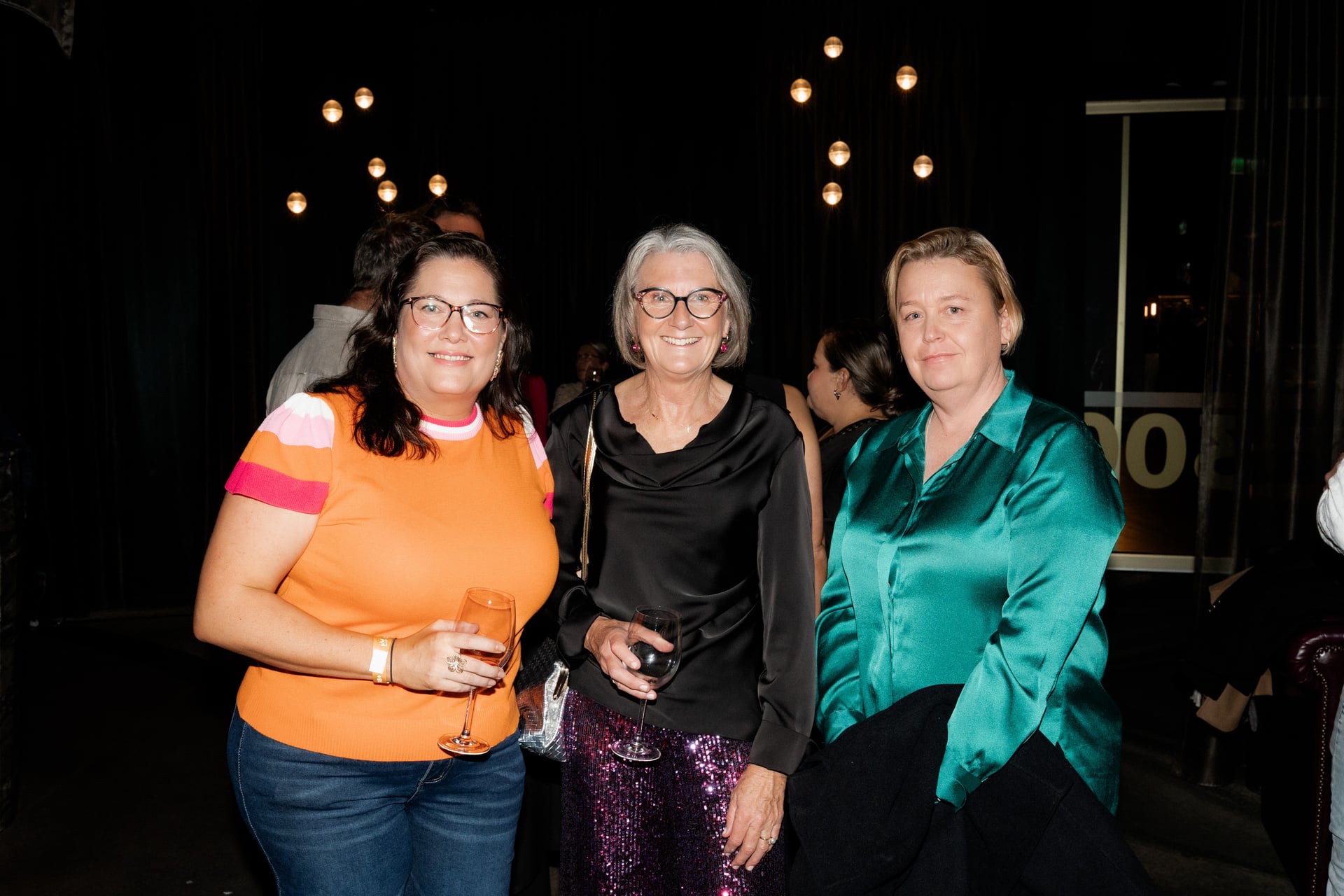 Three guests laughing, drinks in hand