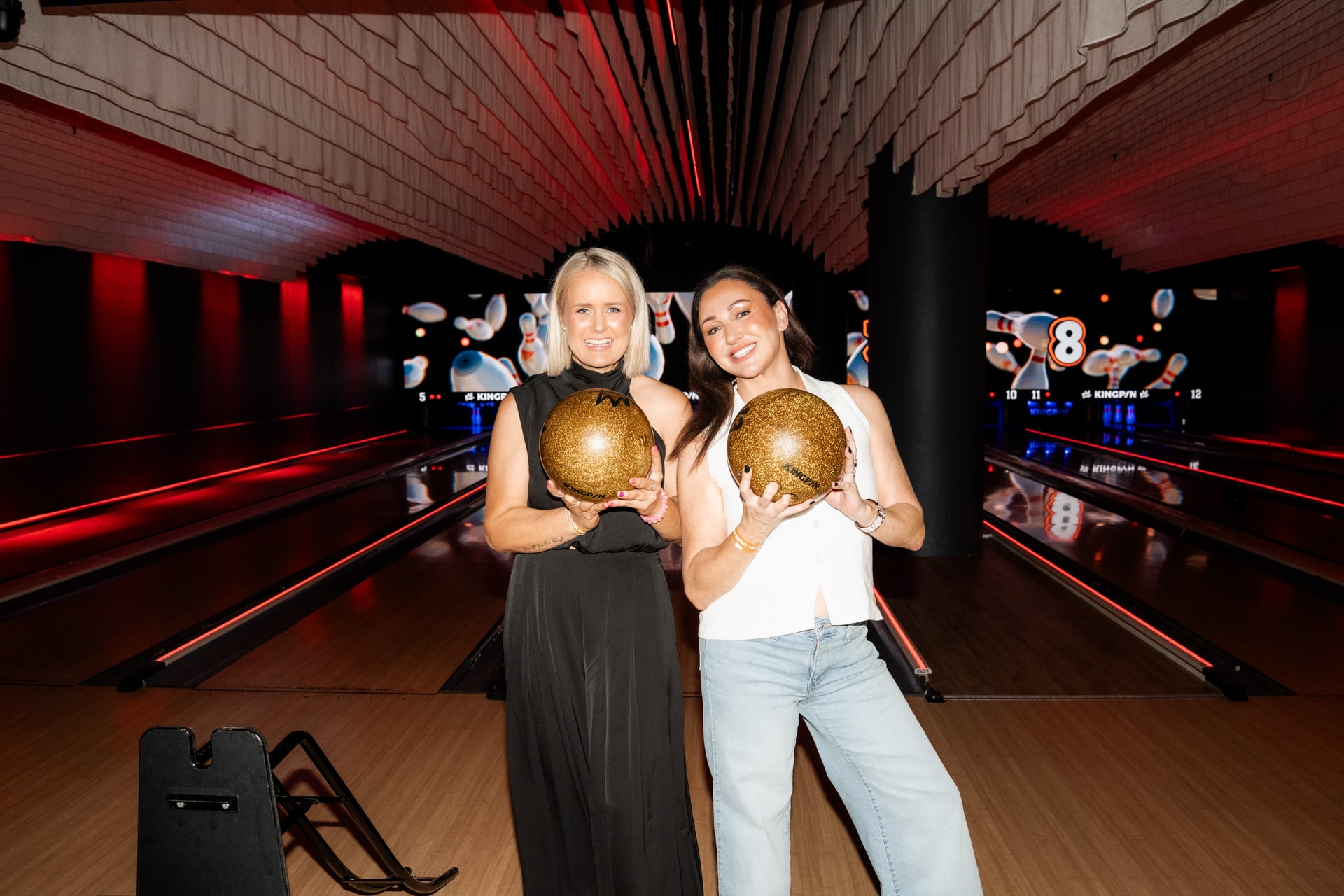 Two founders with gold bowling balls on the lane